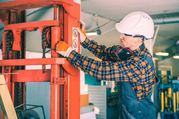 Forklift Repairing Lifting System. Caucasian Worker Fixing the Machine.